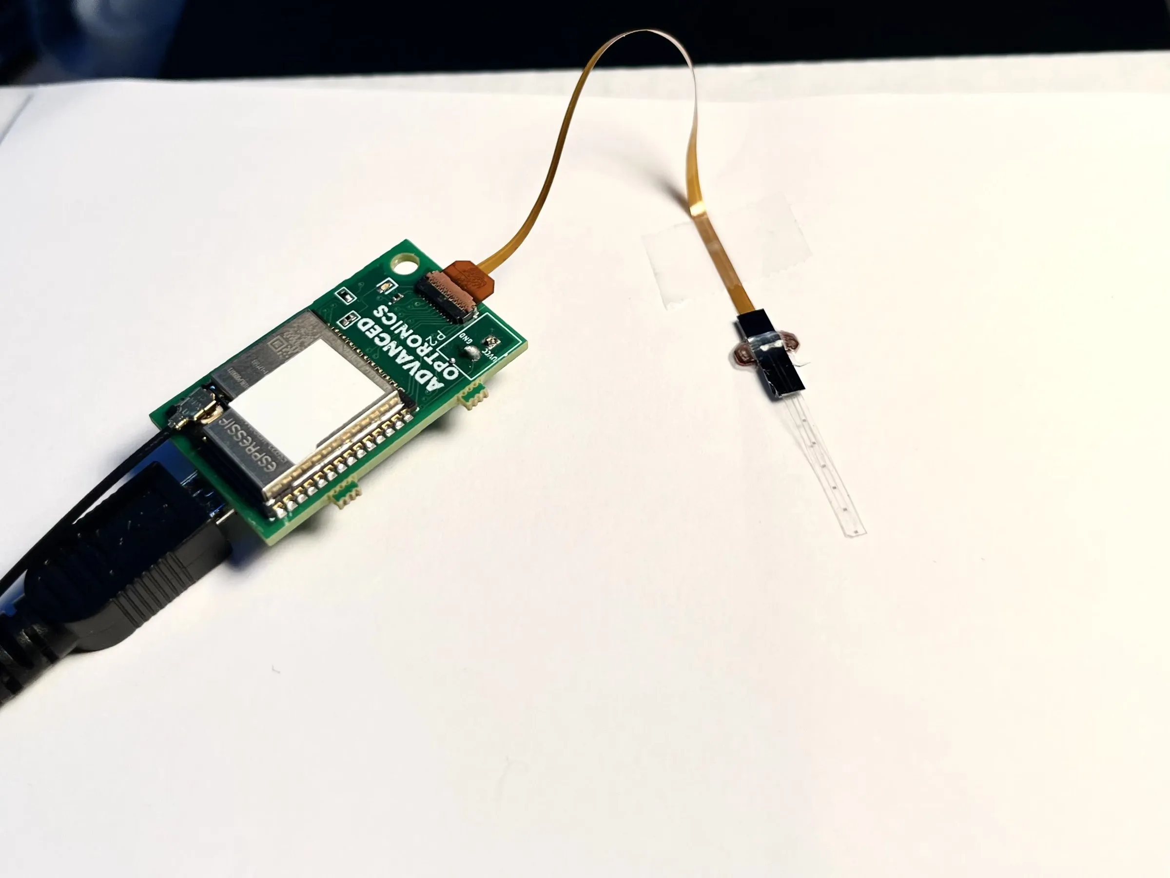 An Advanced Optronics readout board wired to a thin-film sensor on its flex cable.